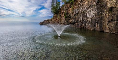 Kasco Solar VFX Display Fountain Pond Aerator spraying water in pond near rocky shoreline for efficient aeration