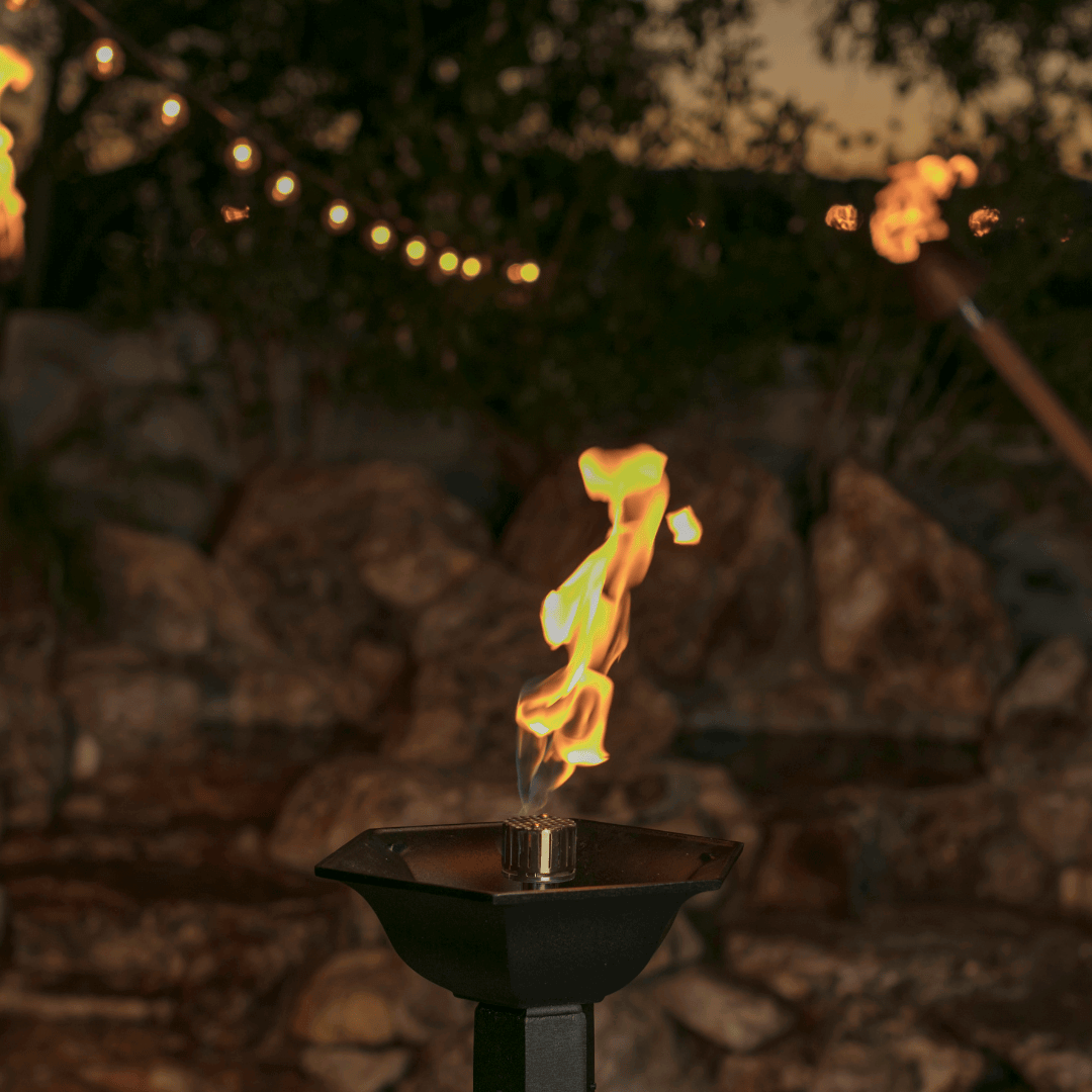 automated coastal tiki torch burning at dusk, modern Gulf tiki torch with warm flame in outdoor patio setting