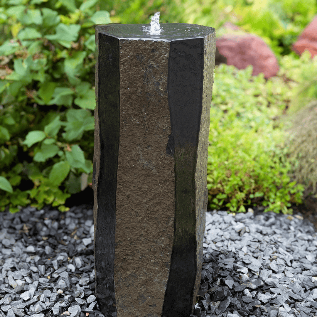 polished sides basalt column outdoor fountain with water bubbling from top, polished and natural faces, garden gravel base