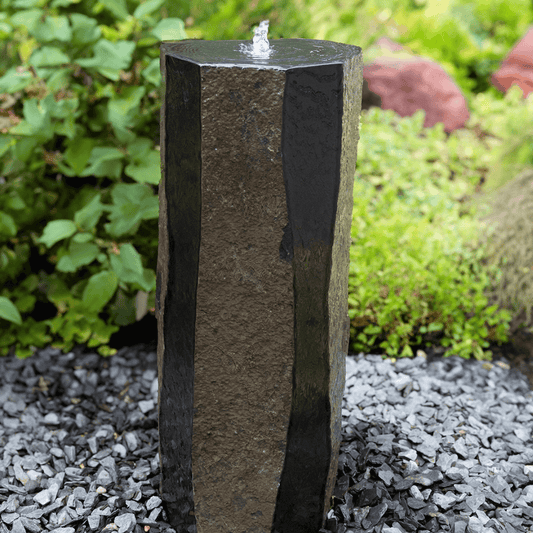 polished sides basalt column outdoor fountain with water bubbling from top, polished and natural faces, garden gravel base
