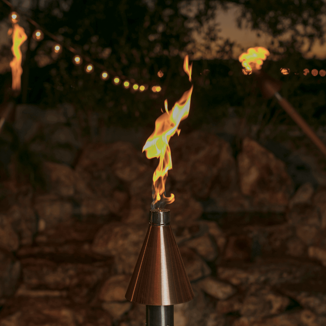 automated copper tiki torch with bright flame on outdoor patio at dusk, copper cone top adding warmth and ambiance