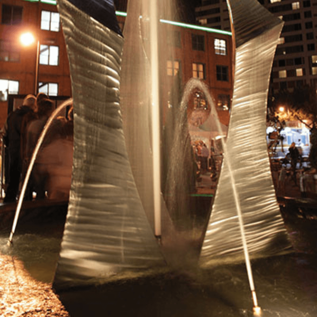 Stainless steel foam jet fountain nozzle creating thick foaming geyser in modern outdoor water feature at night