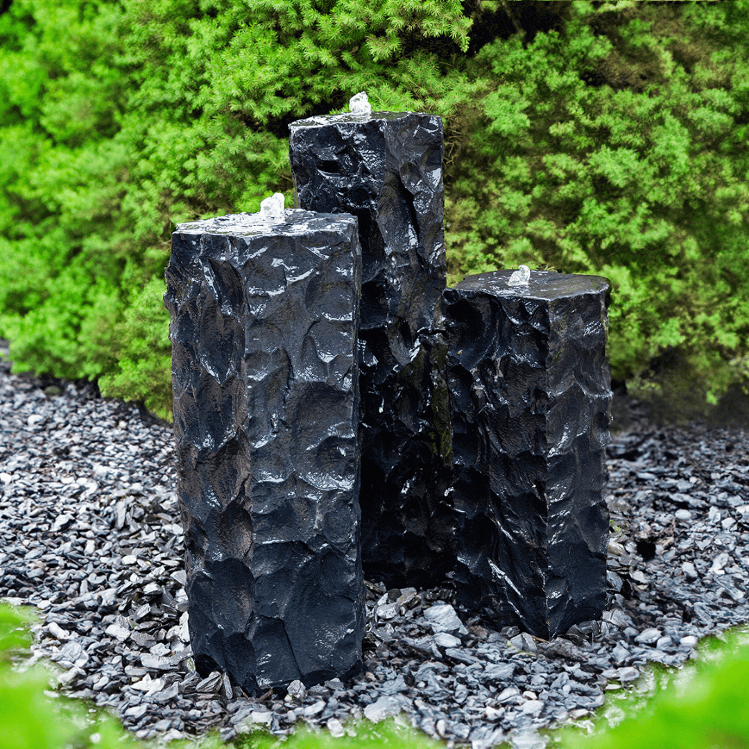 Textured midnight basalt column fountain kit trio with bubbling water feature in garden landscaping