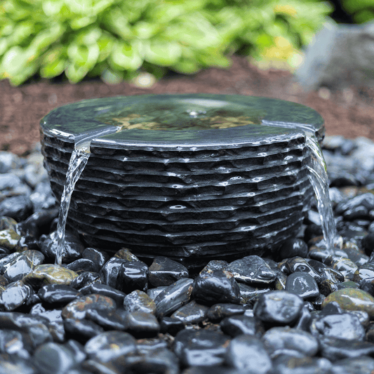 Infinity Bowl fountain with water spilling evenly over its stacked slate rim into black river rock