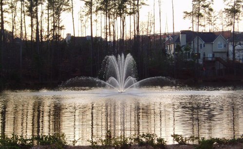 Otterbine Genesis floating pond fountain spraying multiple jets in a lake at sunset, enhancing pond aeration and water circulation