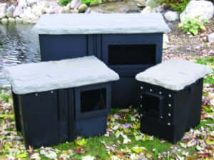 Easypro small pond skimmer with filter pad shown as black skimmer boxes with lids beside a pond on grass