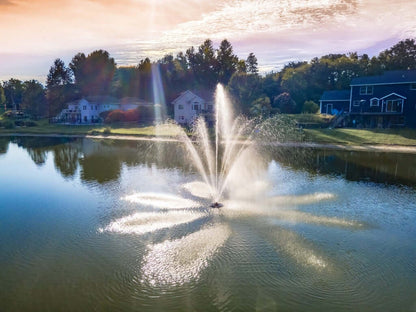 Scott Aerator Solar Atriarch 1/2 HP solar pond fountain creating a 9-jet spray pattern display on a lake near homes