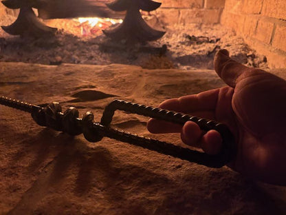 Good Works Hand Twisted Fire Poker shown in a rustic setting, demonstrating its durable craftsmanship.
