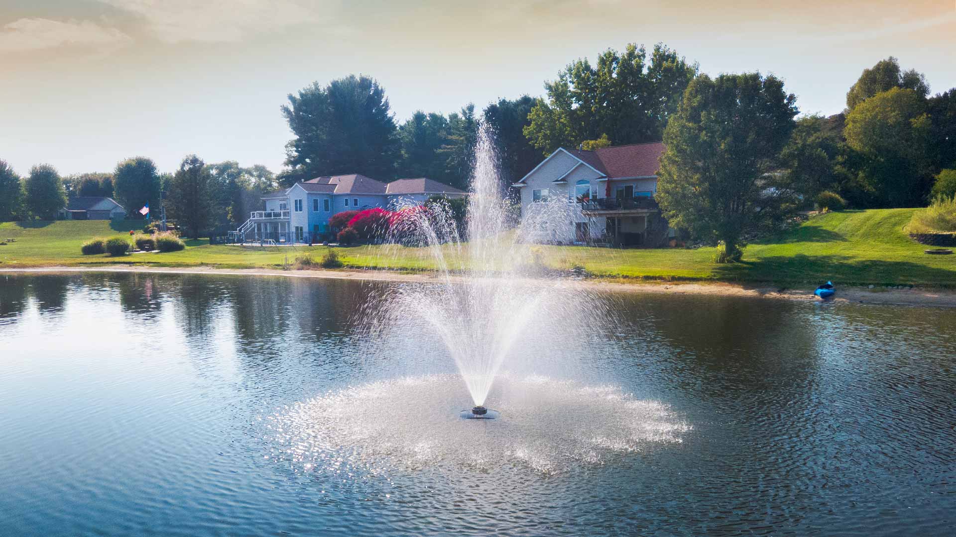 Scott Aerator Solar Amherst pond fountain spraying three-tier display in lake, 15 ft center column and wide 30 ft surface pattern