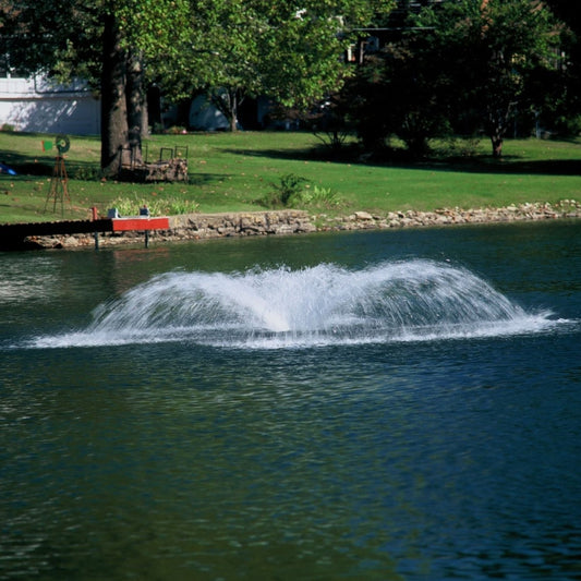Outdoor Water Solutions Aquarian Pro 1/2 HP surface pond aerator spraying a wide white plume on a backyard pond