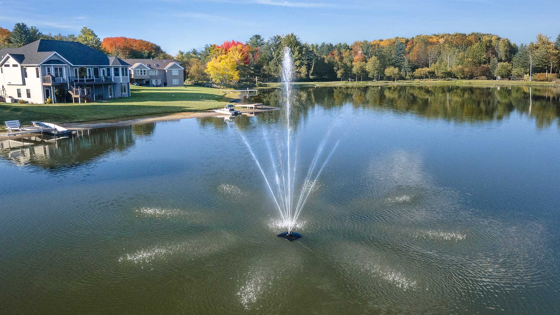 Scott Aerator Solar Atriarch 1/2 HP solar pond fountain creating a 9-jet spray pattern on a residential lake with solar panels