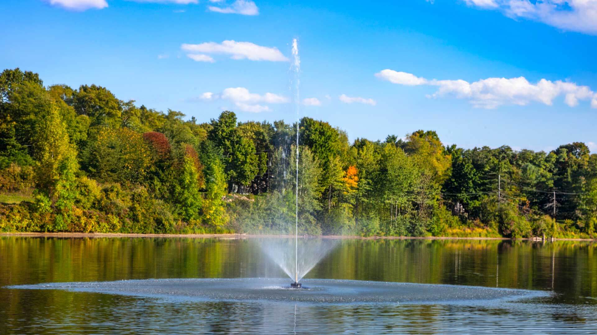 Scott Aerator Solar Skyward 1/2 HP solar pond fountain spraying tall vertical jet on lake, off-grid two-panel solar system